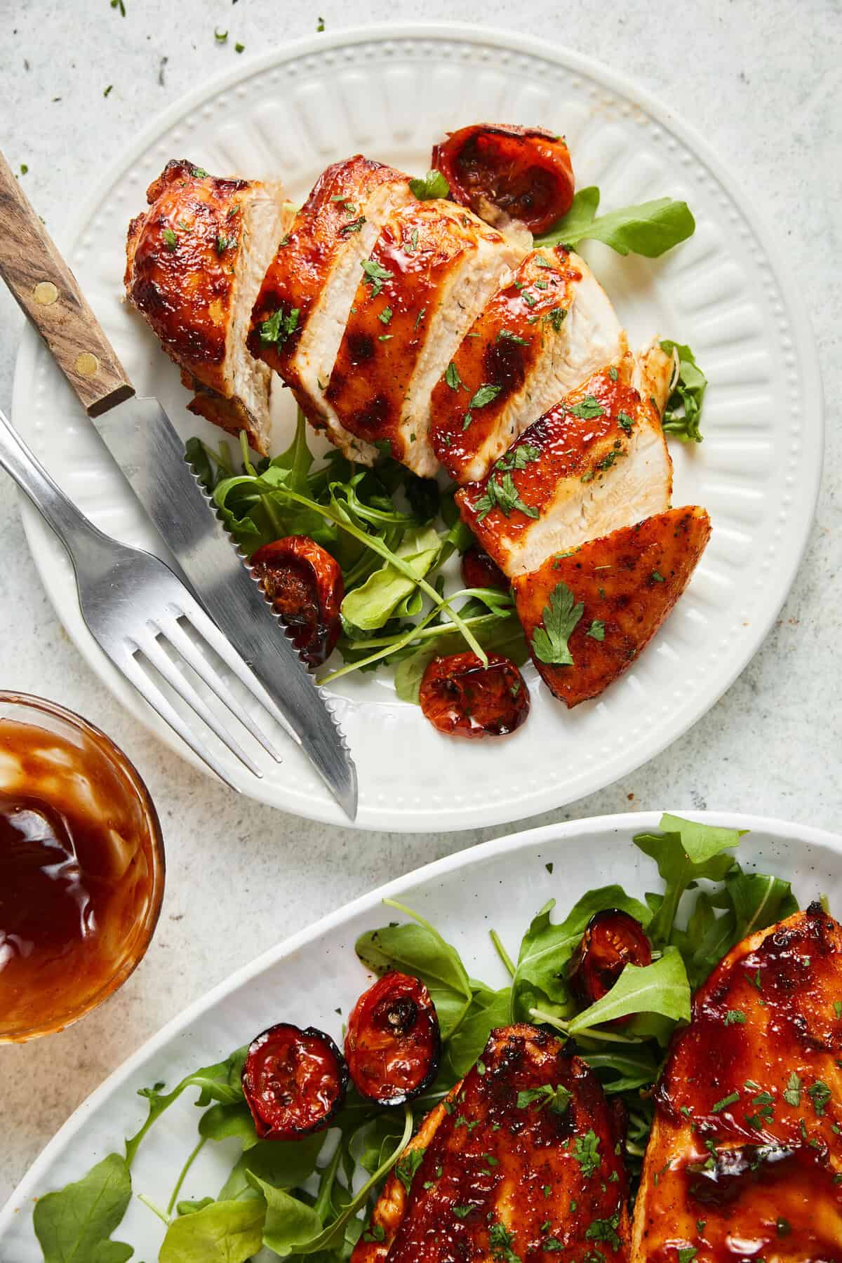 Air-Fryer BBQ chicken breast, sliced and served on a bed of arugula with roasted tomatoes.