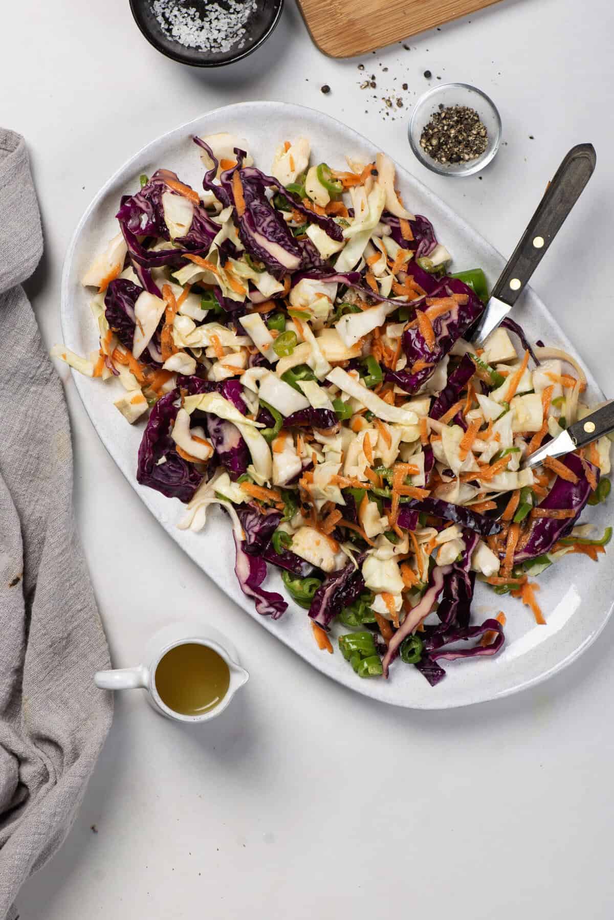 Jalape&ntilde;o coleslaw on a white platter, featuring shredded cabbage, carrots, and sliced jalape&ntilde;os.