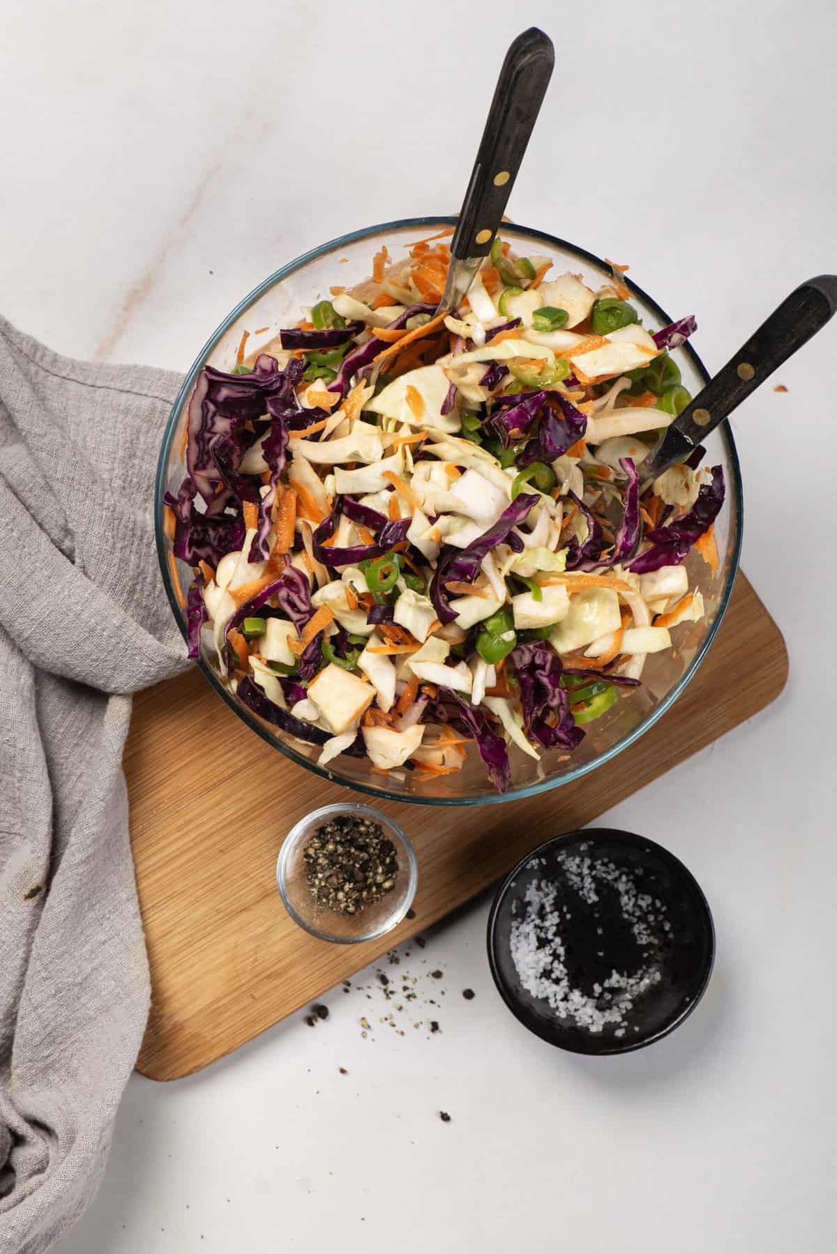 A large glass bowl of colorful jalape&ntilde;o coleslaw with shredded cabbage and carrots.