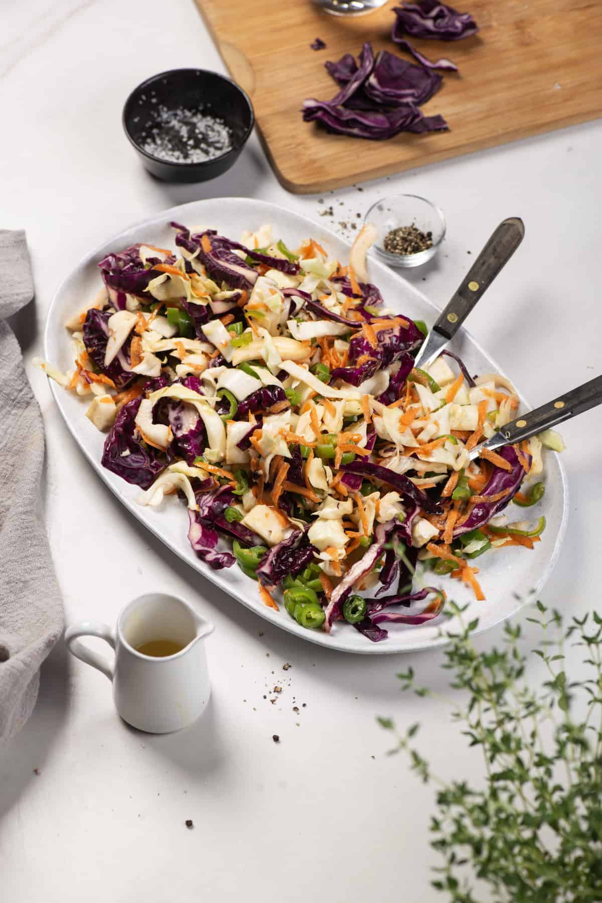 Jalape&ntilde;o coleslaw served on a white oval platter with serving utensils.