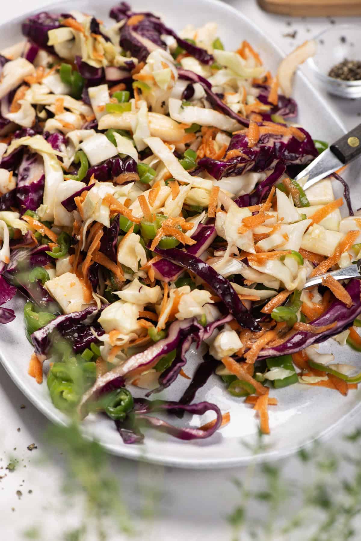 Jalape&ntilde;o coleslaw in a white serving dish, with shredded cabbage, carrots, and green jalape&ntilde;os.