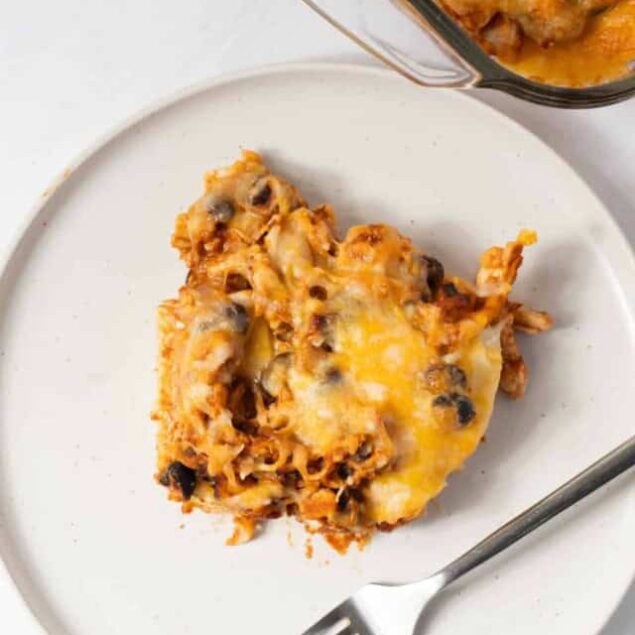 Baked sweet potato casserole with cheese and black beans on a white plate, healthy comfort food.