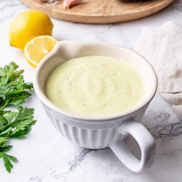 Creamy avocado garlic sauce with fresh lemon and herbs, perfect for adding flavor to salads, tacos, or grilled dishes, via Food Faith Fitness.