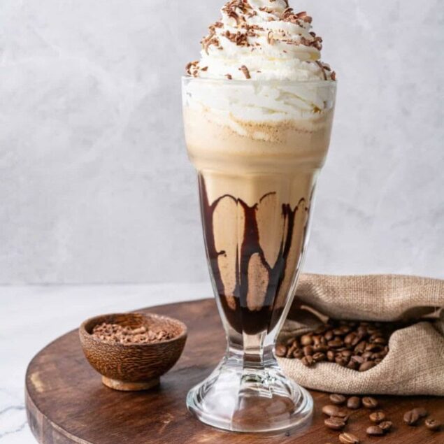 Sweet coffee frappuccino with whipped cream and chocolate shavings in a tall glass. Perfect for coffee lovers, featuring rich flavors and decadent toppings.