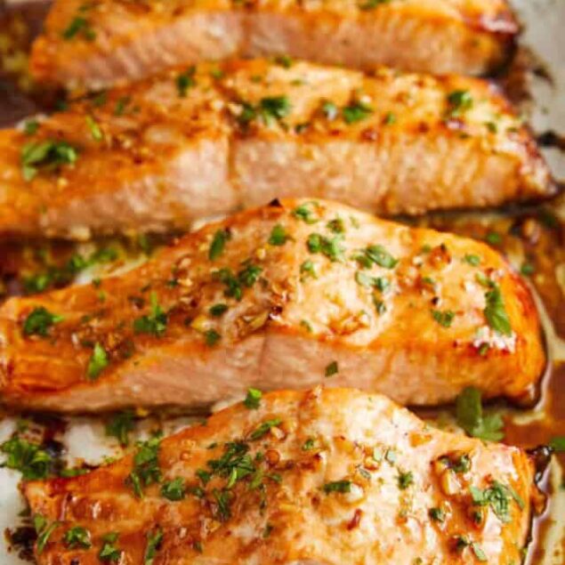 Juicy baked salmon fillets with a garlic herb butter sauce, garnished with fresh parsley for a healthy and delicious seafood meal. Perfect for weekly nutritious dinner options.