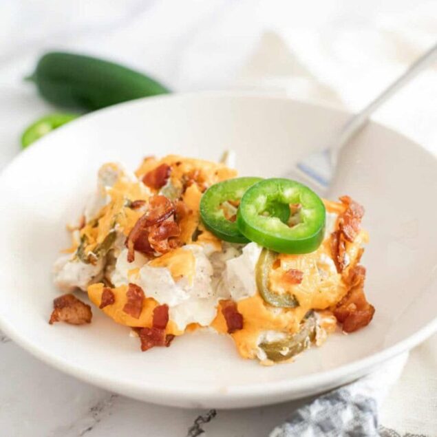 Creamy breakfast casserole with bacon, green peppers, and cheese garnished with sliced jalapeños, served in a white bowl - perfect for easy, healthy meal ideas.