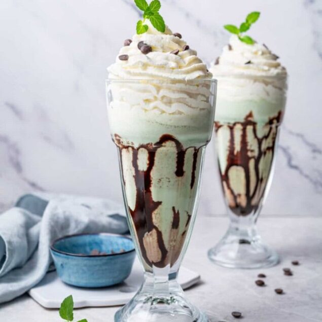 Creamy mint chocolate milkshake with whipped cream, chocolate drizzle, and fresh mint garnish - a delicious and indulgent treat.