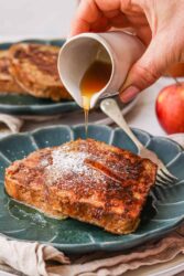 Gluten-Free French toast on a teal plate, topped with powdered sugar and drizzled with syrup.
