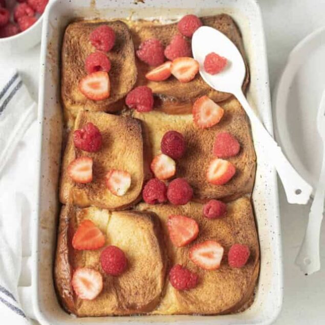French toast casserole topped with fresh strawberries and raspberries, served in a white baking dish, perfect for healthy breakfast recipes and nutritious meal ideas.