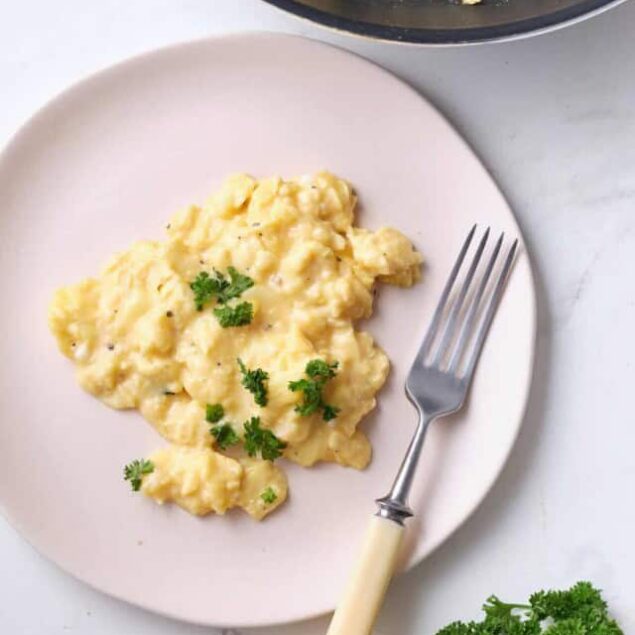 Creamy scrambled eggs garnished with fresh parsley, served on a white plate for a healthy breakfast option. Perfect for high-protein, nutritious meal ideas.