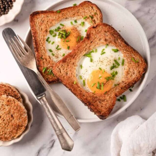Soft-boiled eggs baked in bread, served on whole wheat toast with chopped green onions, healthy breakfast idea, nutritious and easy recipe, rustic kitchen presentation.