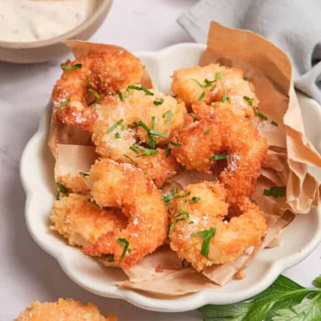 Crispy coconut shrimp served with fresh herbs and dipping sauce, perfect for healthy eating or entertaining guests. Delicious, gluten-free seafood appetizer from Food Faith Fitness.
