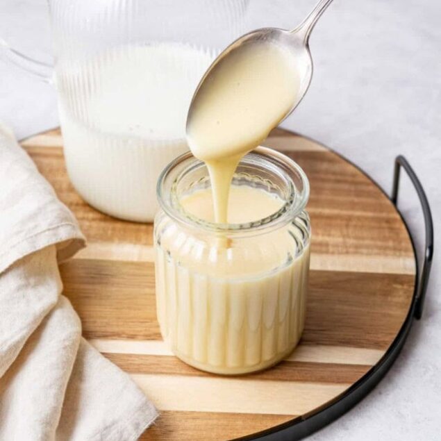 Creamy homemade condensed milk being poured into a glass jar, perfect for healthy dessert recipes and baking. Ideal for food lovers seeking nutritious and delicious homemade sweeteners.