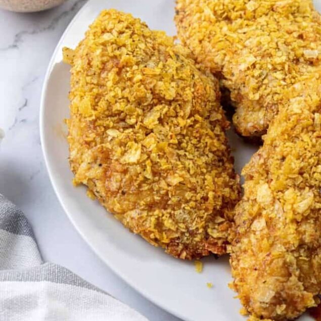 Crispy baked chicken tenders with golden breading served on a white plate, perfect for a healthy meal or snack.