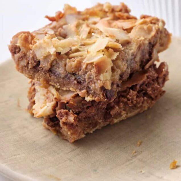 Butter pecan blondie with toasted pecans and caramelized brown sugar on top, served on a beige plate.