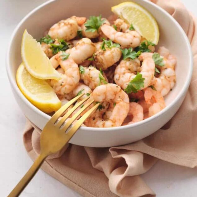 Succulent shrimp served with lemon wedges, fresh herbs, and a drizzle of olive oil in a white bowl, perfect for healthy seafood dishes on Food Faith Fitness.