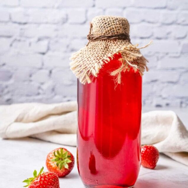 Fresh strawberry infused water in a glass jar with a rustic fabric cover for a healthy diet and hydration at Food Faith Fitness.