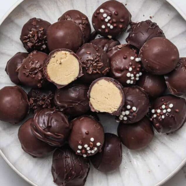 Chocolate protein truffles with a creamy filling, topped with sprinkles and chocolate coating, perfect for healthy snacks or dessert recipes.