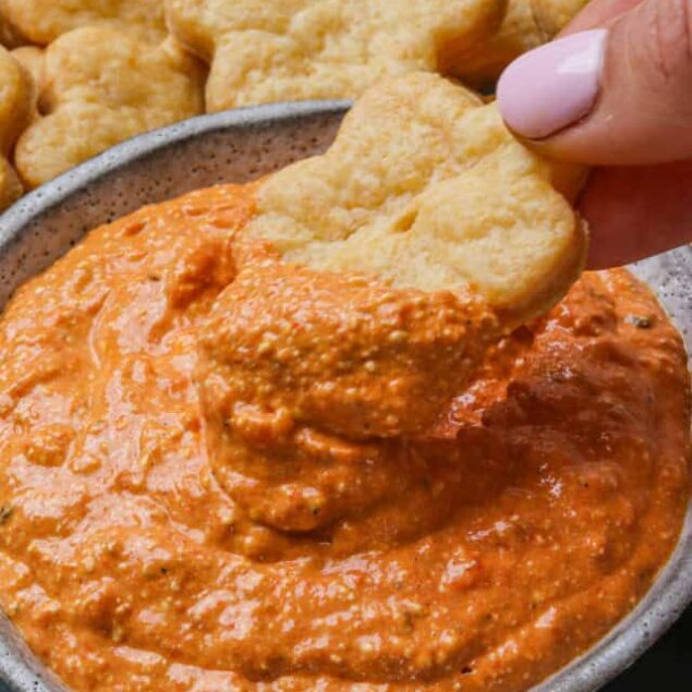 Creamy vegan peanut butter and tomato dip with sprouted grain crackers for healthy snack ideas.