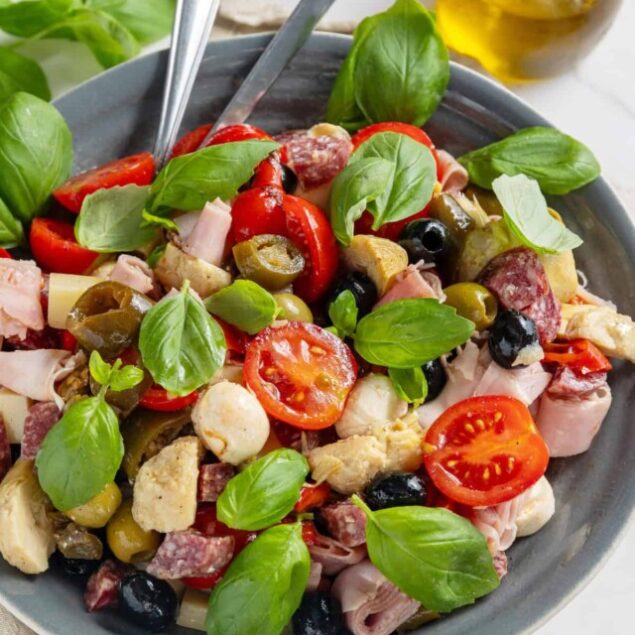 Fresh Mediterranean chicken salad with cherry tomatoes, olives, basil, and cheese, served in a gray bowl; healthy, flavorful recipe often featured on Food Faith Fitness.