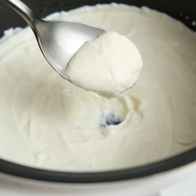 Cream cheese being scooped from a mixing bowl, showcasing a healthy and delicious dairy-based ingredient. Perfect for recipes focusing on high-protein, low-carb, or keto-friendly meals.