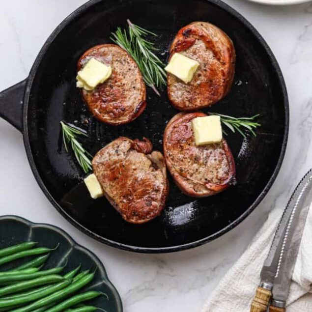 Juicy skillet pork chops topped with butter and fresh rosemary, served alongside green beans for a healthy, flavorful meal. Perfect for quick weeknight dinners with easy side options.