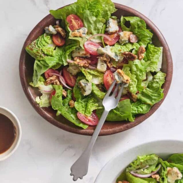 Fresh garden salad with cherry tomatoes, blue cheese crumbles, walnuts, and mixed greens, served in a rustic bowl for a healthy meal.