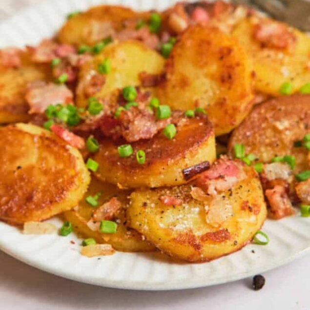Crispy pan-fried potato cakes topped with bacon and green onions, served on a white plate, healthy breakfast or snack, easy recipe, gluten-free comfort food, Food Faith Fitness.