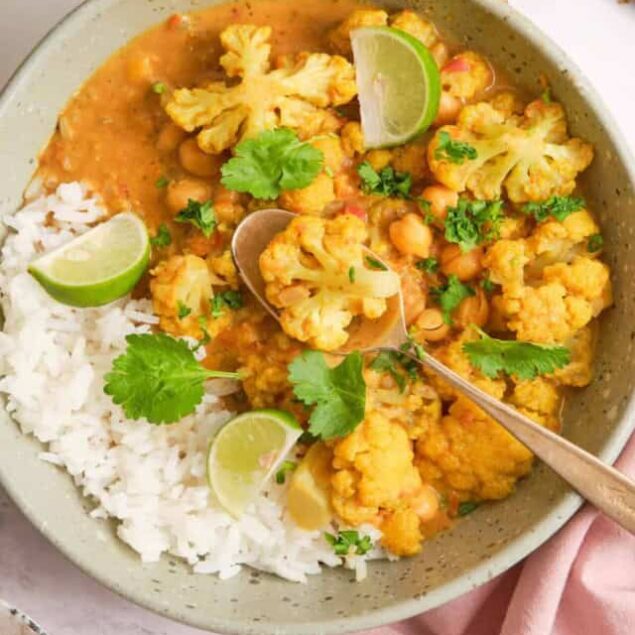 Creamy cauliflower chickpea curry with rice, garnished with fresh cilantro and lime wedges, healthy vegetarian Indian-inspired dish, gluten-free vegan meal, Food Faith Fitness recipe.