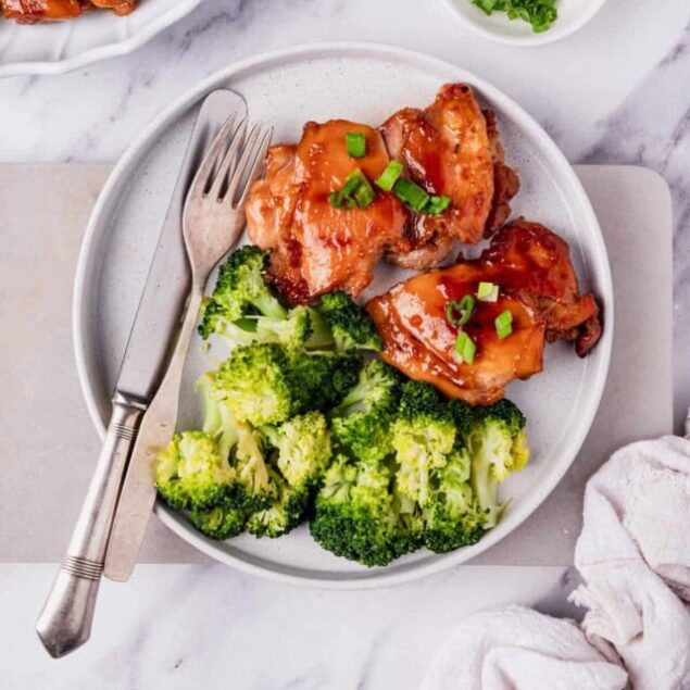Grilled chicken with brown sauce served with steamed broccoli, healthy and delicious meal with fresh green onions on top, perfect for a nutritious dinner.