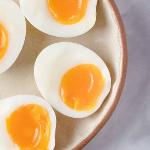 Soft boiled eggs with runny yolks in a ceramic bowl, healthy breakfast idea with protein-rich food, perfect for meal prep or a nutritious start to your day.