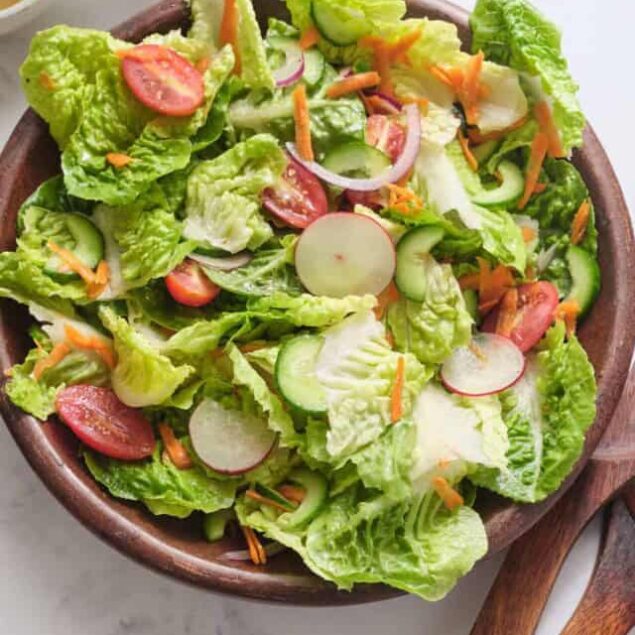 Fresh garden salad with crisp lettuce, cherry tomatoes, cucumber, radishes, and shredded carrots in a wooden bowl. Perfect for healthy eating and weight loss.