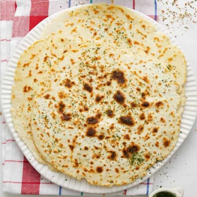 Fluffy homemade quesadilla with crispy golden edges, garnished with herbs and served on a paper plate for a healthy snack or meal option.