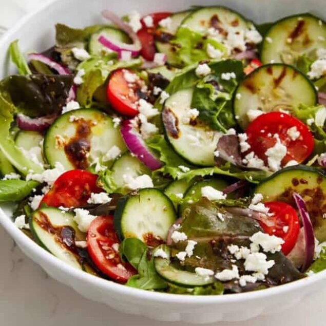 Fresh vegetable salad with cherry tomatoes, cucumber, red onion, feta cheese, and mixed greens for healthy eating.