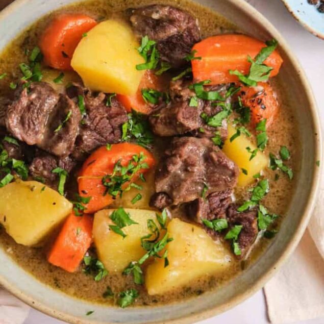 Hearty beef stew with potatoes, carrots, and fresh herbs in a flavorful broth, perfect for healthy comfort food recipes and meal prep.