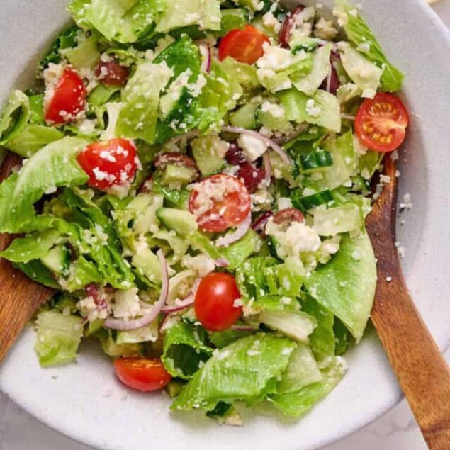 Fresh vegetable salad with cherry tomatoes, lettuce, cucumbers, red onions, and feta cheese, offering a healthy, nutrient-packed meal option.
