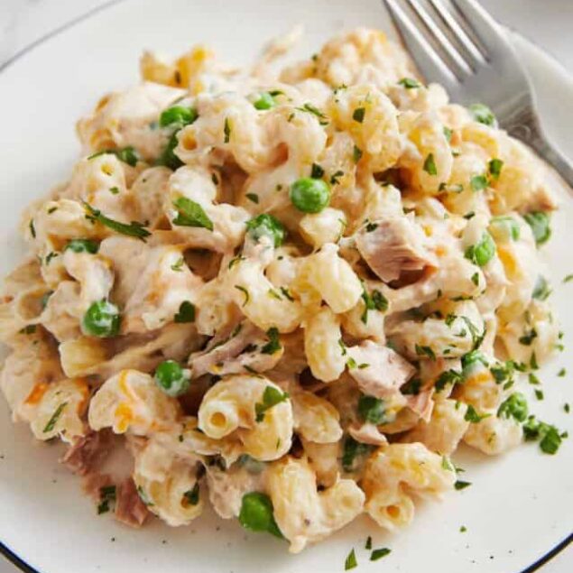 Creamy tuna pasta salad with green peas and fresh herbs, perfect for healthy meals and easy lunch ideas. Delicious, nutritious seafood dish served on a white plate.