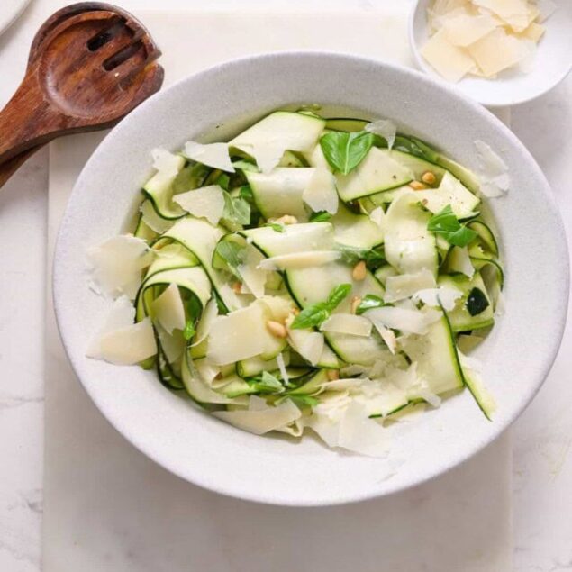 Fresh zucchini noodles with Parmesan cheese and basil for healthy, low-carb eating. Perfect for nutritious meal prep and gluten-free diets.