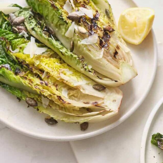 Roasted romaine lettuce salad with shredded coconut and sunflower seeds, fresh lemon wedge, healthy vegan side dish, gluten-free, nutritious meal idea.