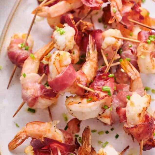 Succulent bacon-wrapped shrimp skewers garnished with chopped chives, perfect for healthy grilling recipes and appetizer ideas in keto diet meal plans.
