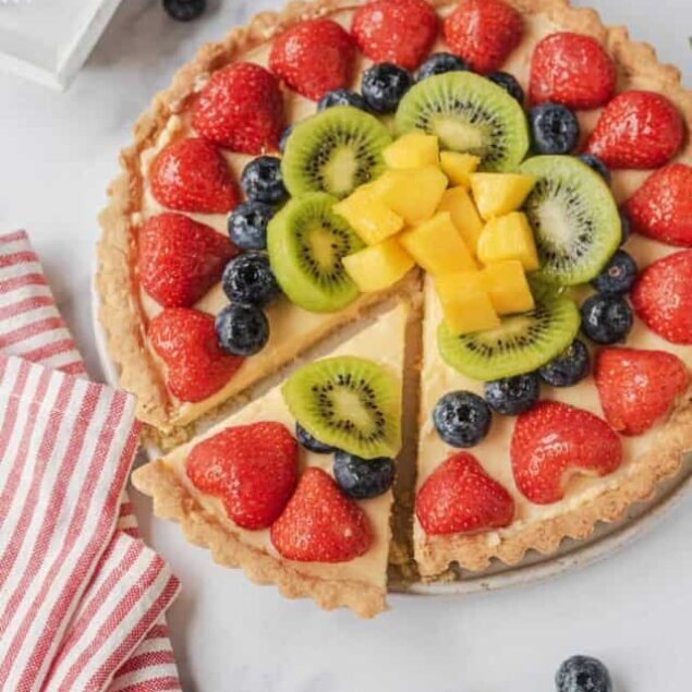 Fresh fruit tart with strawberries, blueberries, kiwi, and mango on a flaky crust, perfect for healthy desserts and fruit-filled recipes.