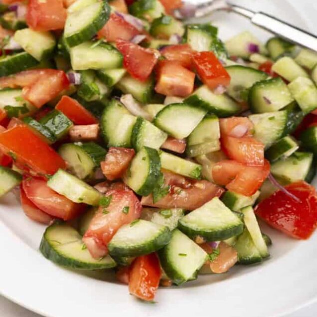 Fresh cucumber tomato salad with red onions and herbs, healthy and refreshing vegetarian dish. Perfect for summer picnics or light meals, easy to prepare with fresh ingredients.