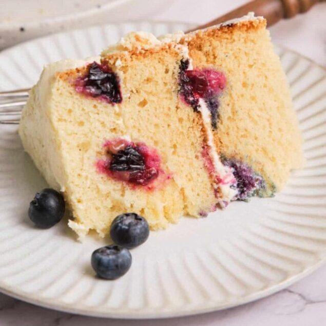 Light and fluffy blueberry cake with creamy frosting, fresh blueberries topping, ideal for healthy dessert options from Food Faith Fitness.