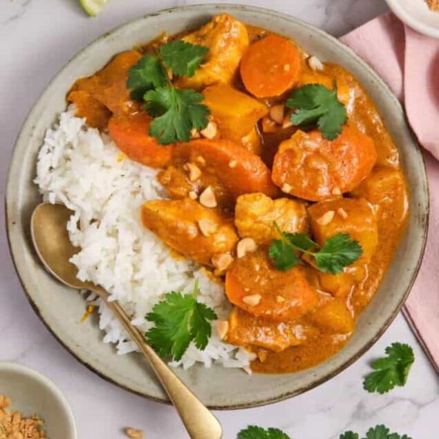 Creamy chicken curry with vegetables served over white rice, garnished with cilantro and chopped nuts, perfect for healthy meal prep and delicious Indian-inspired cuisine.