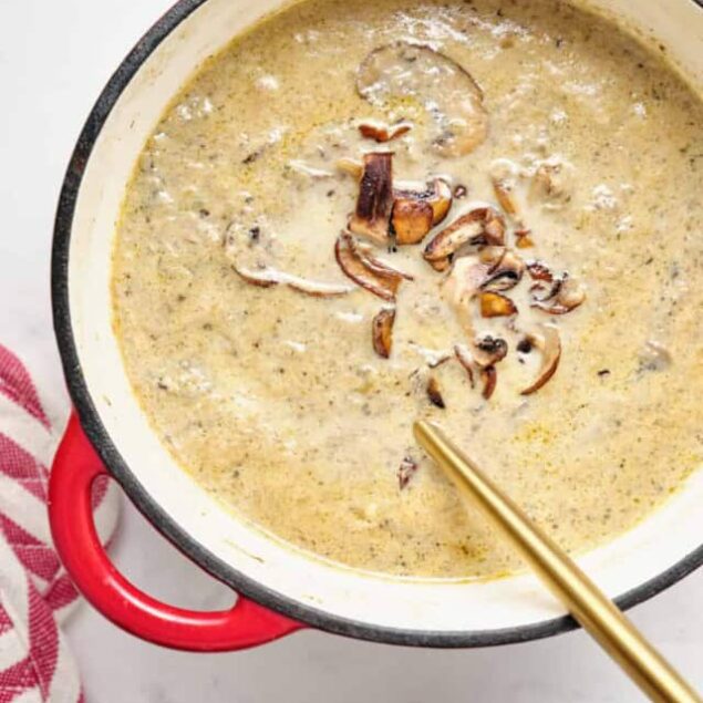 Creamy mushroom soup with sautéed mushrooms in a red-enamel cast iron pot, perfect for healthy comfort food recipes and easy dinner ideas.