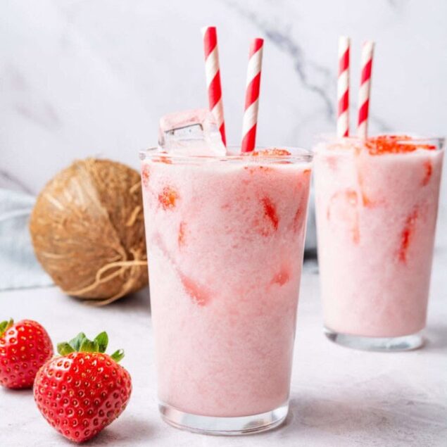 Strawberry coconut smoothie with red and white striped straws and fresh strawberries, healthy fruit smoothie, vegan and gluten-free drink, delicious summer beverage, Food Faith Fitness.