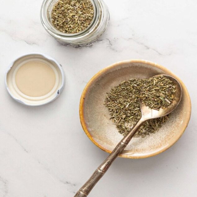 Dried herbs and herbal tea with honey on a white marble surface for healthy, natural food recipes.