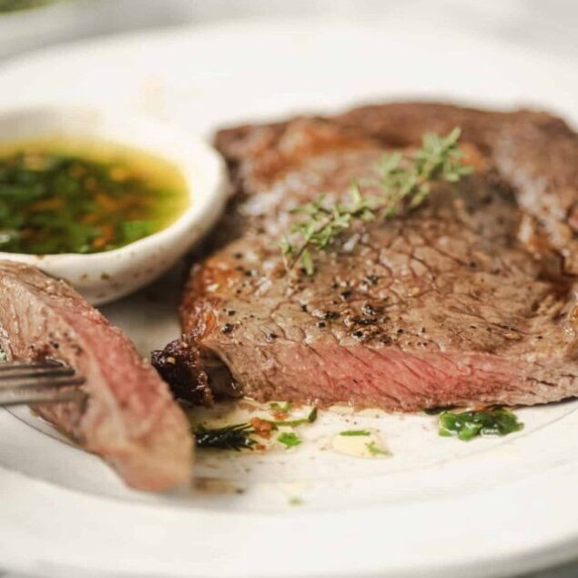 Juicy cooked steak with fresh herbs and dipping sauce, perfect for healthy eating and delicious meal ideas in food and fitness lifestyle.