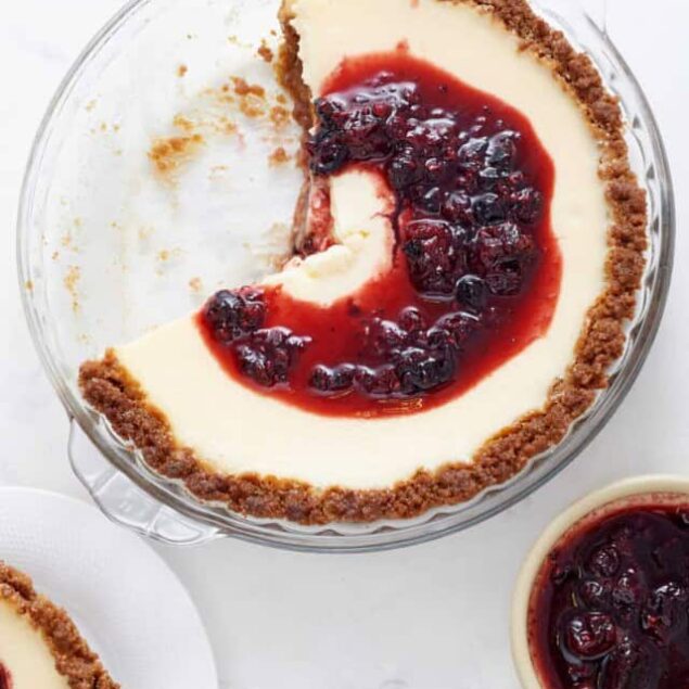 Creamy cheesecake with cherry topping in a glass baking dish, featuring a graham cracker crust, perfect for dessert recipes and holiday gatherings.