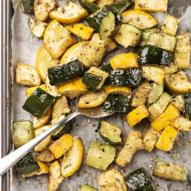 Roasted zucchini and yellow squash with herbs and seasoning on baking sheet, healthy vegetable side dish for weight loss or low-calorie meals.